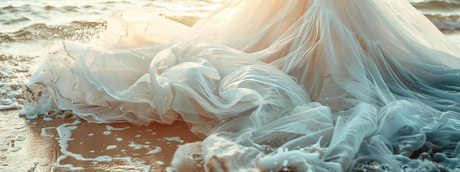 a Flowing White Bridal Dress Billowing in the Ocean Breeze, with Soft Sand and Gentle Waves in the Background. - Scarlet Poppy Bridal Boutique - Scarlet Poppy Bridal Boutique