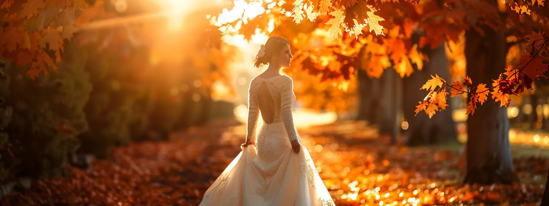 a Breathtaking Autumn Landscape Showcases a Bride in an Exquisite Designer Dress, Adorned with Vibrant Leaves and Soft Golden Sunlight, Embodying Timeless Elegance and Seasonal Beauty. - Scarlet Poppy Bridal Boutique - Scarlet Poppy Bridal Boutique