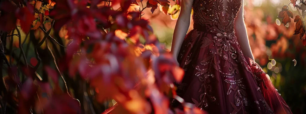 a Breathtaking Autumn Wedding Gown in Rich Burgundy Silk, Featuring a Stunning Fit and Flare Silhouette Adorned with Delicate Sequin Embellishments, Elegantly Displayed Against a Backdrop of Vibrant Fall Foliage, Capturing the Essence of Seasonal Romance. - Scarlet Poppy Bridal Boutique - Scarlet Poppy Bridal Boutique
